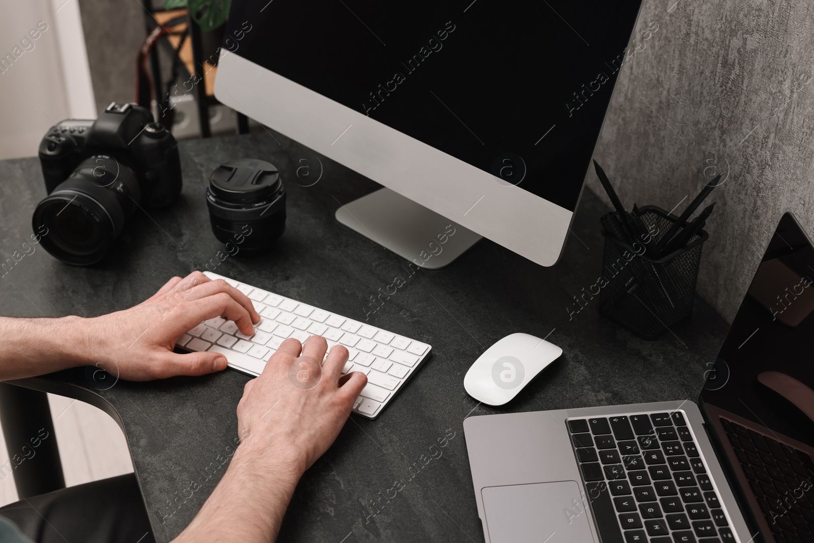 Photo of Photographer working on computer at dark table with camera, closeup