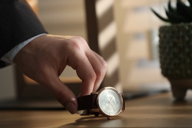 Photo of Man putting luxury wrist watch on table, closeup