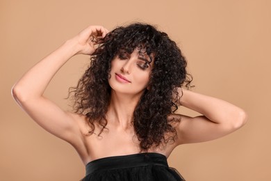 Photo of Beautiful young woman with long curly hair on beige background
