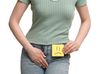 Photo of Woman holding sticky note with drawn sad face and suffering from cystitis on white background, closeup