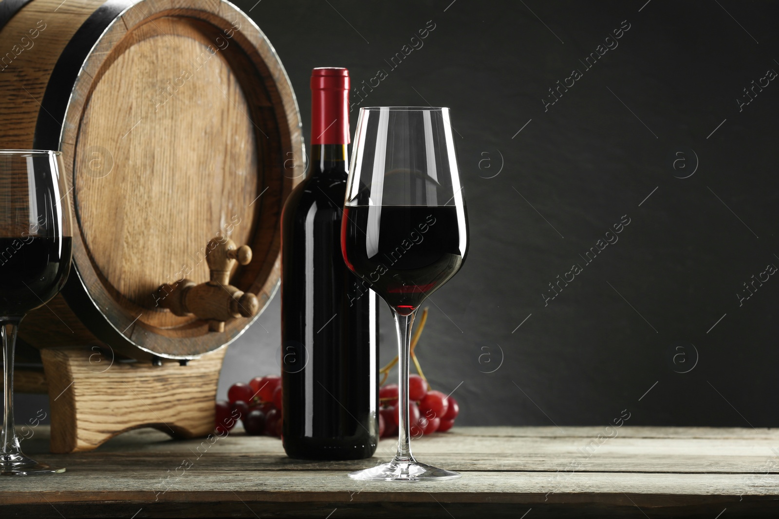 Photo of Winemaking. Composition with tasty wine and barrel on wooden table against gray background, space for text