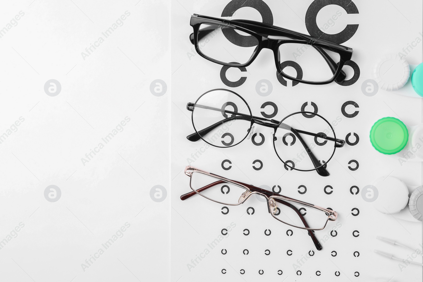 Photo of Vision test chart, glasses, lenses and tweezers on white background, flat lay. Space for text