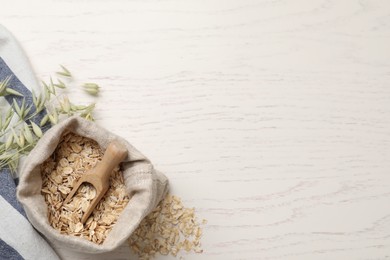 Photo of Oatmeal and branches with florets on white wooden table, flat lay. Space for text