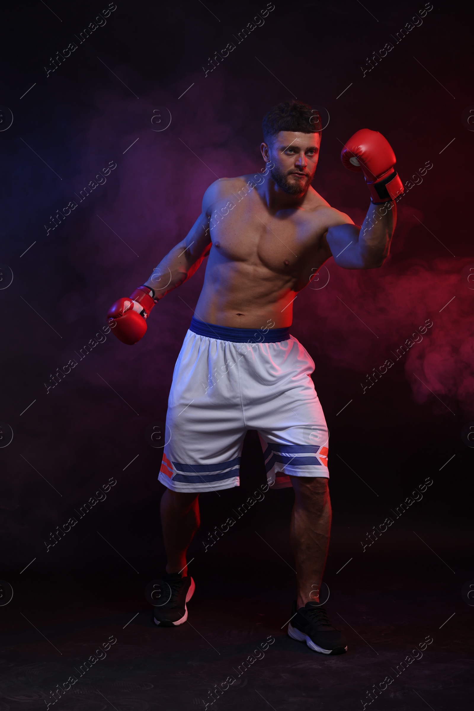 Photo of Man wearing boxing gloves fighting on dark background