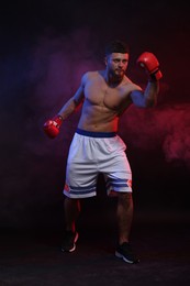 Man wearing boxing gloves fighting on dark background