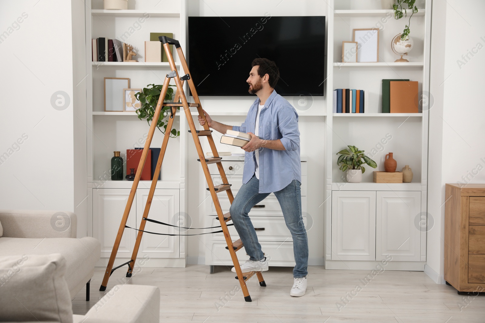 Photo of Man with books near wooden folding ladder at home