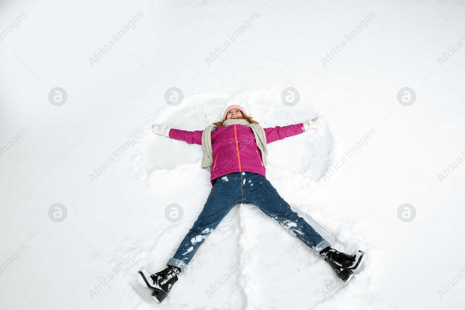 Photo of Beautiful woman making snow angel on winter day
