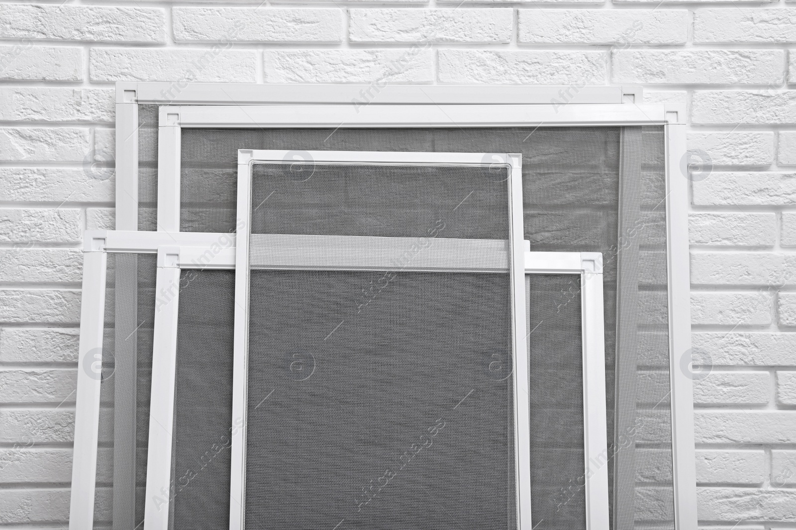 Photo of Set of window screens near white brick wall