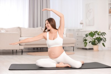 Pregnant woman doing exercises on yoga mat at home