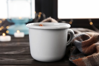 Photo of Composition with cup of hot winter drink and scarf on wooden sill near window. Cozy season