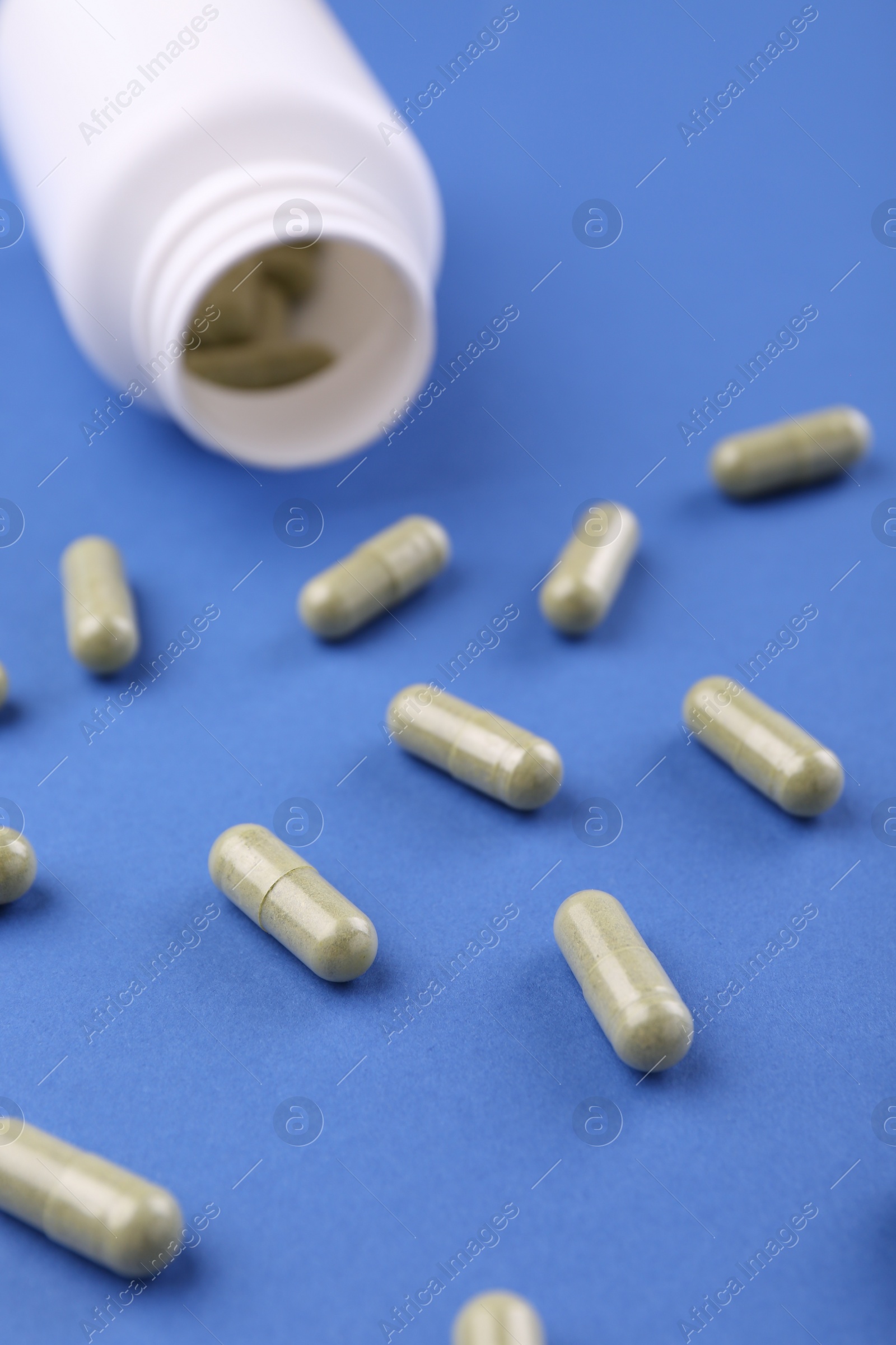 Photo of Bottle and vitamin capsules on blue background, closeup