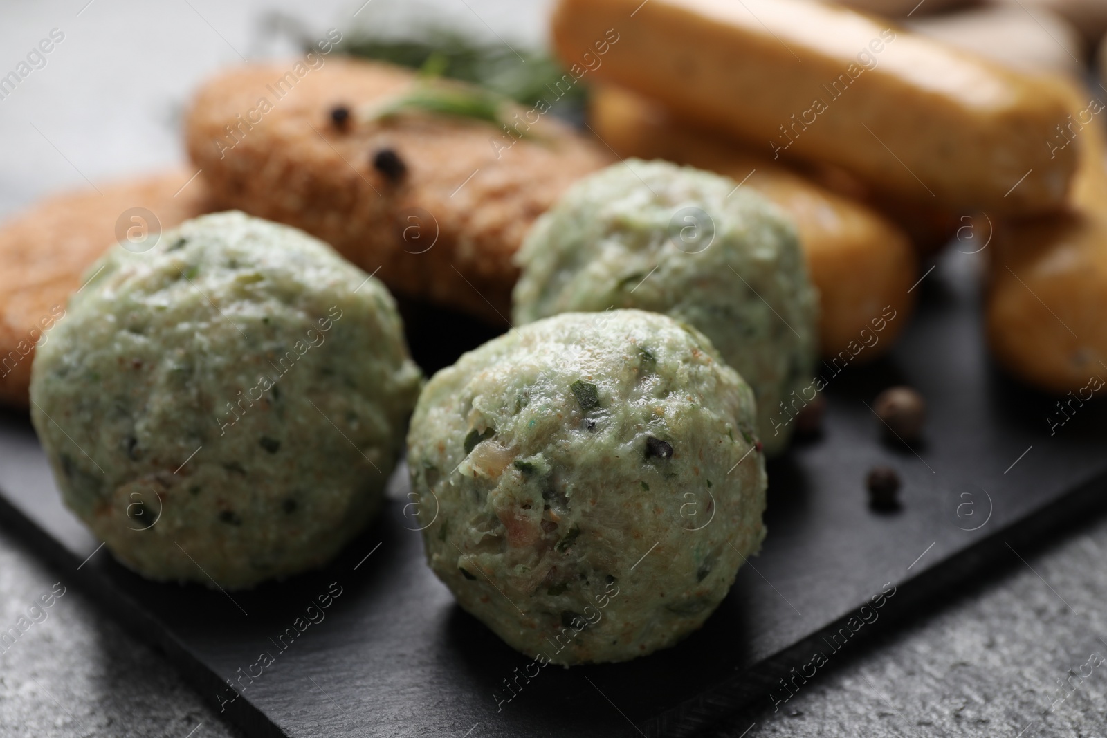 Photo of Falafel balls and different raw vegan meat products on dark board, closeup