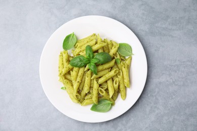 Delicious pasta with pesto sauce and basil on light grey table, top view