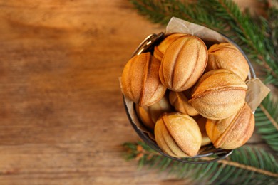 Delicious nut shaped cookies and fir branches on wooden table, flat lay. Space for text
