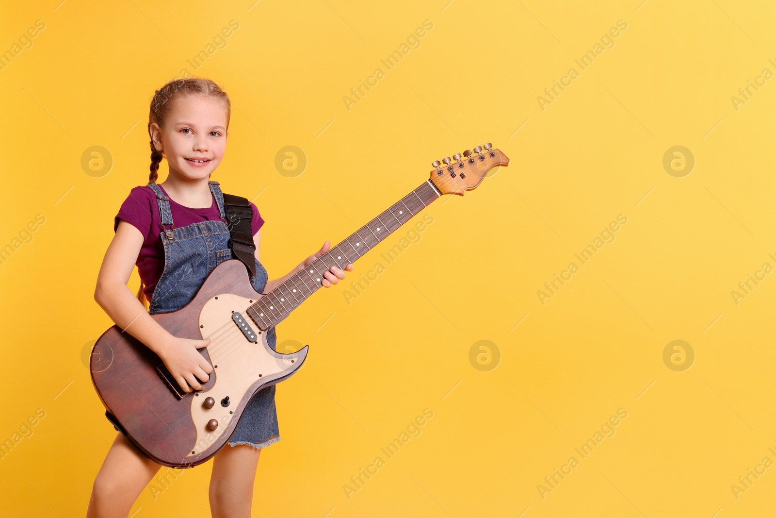 Photo of Cute girl with electric guitar on orange background. Space for text