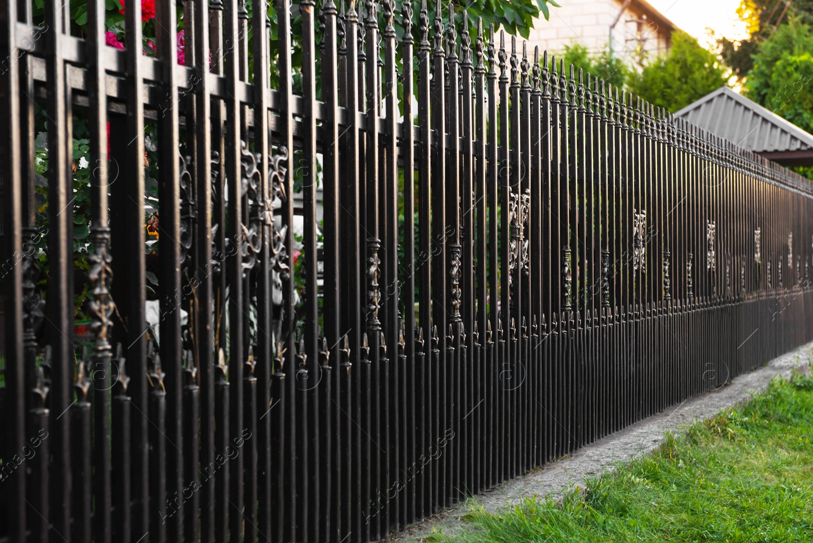 Photo of Beautiful black iron fence near pathway outdoors