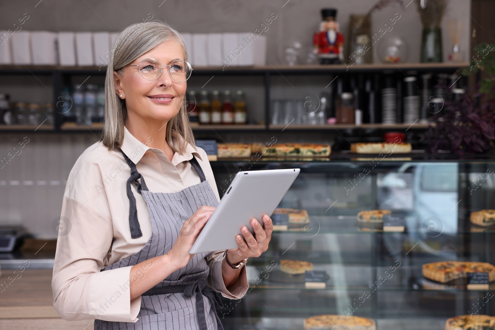 Photo of Happy business owner using tablet in her cafe, space for text