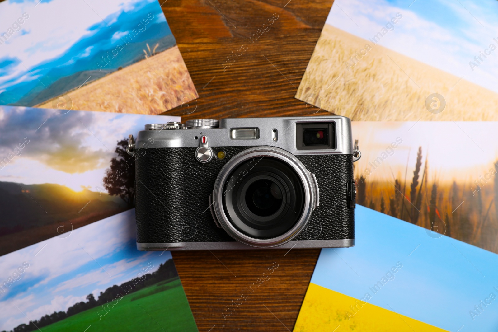 Photo of Vintage photo camera and beautiful printed pictures on wooden table, flat lay. Creative hobby