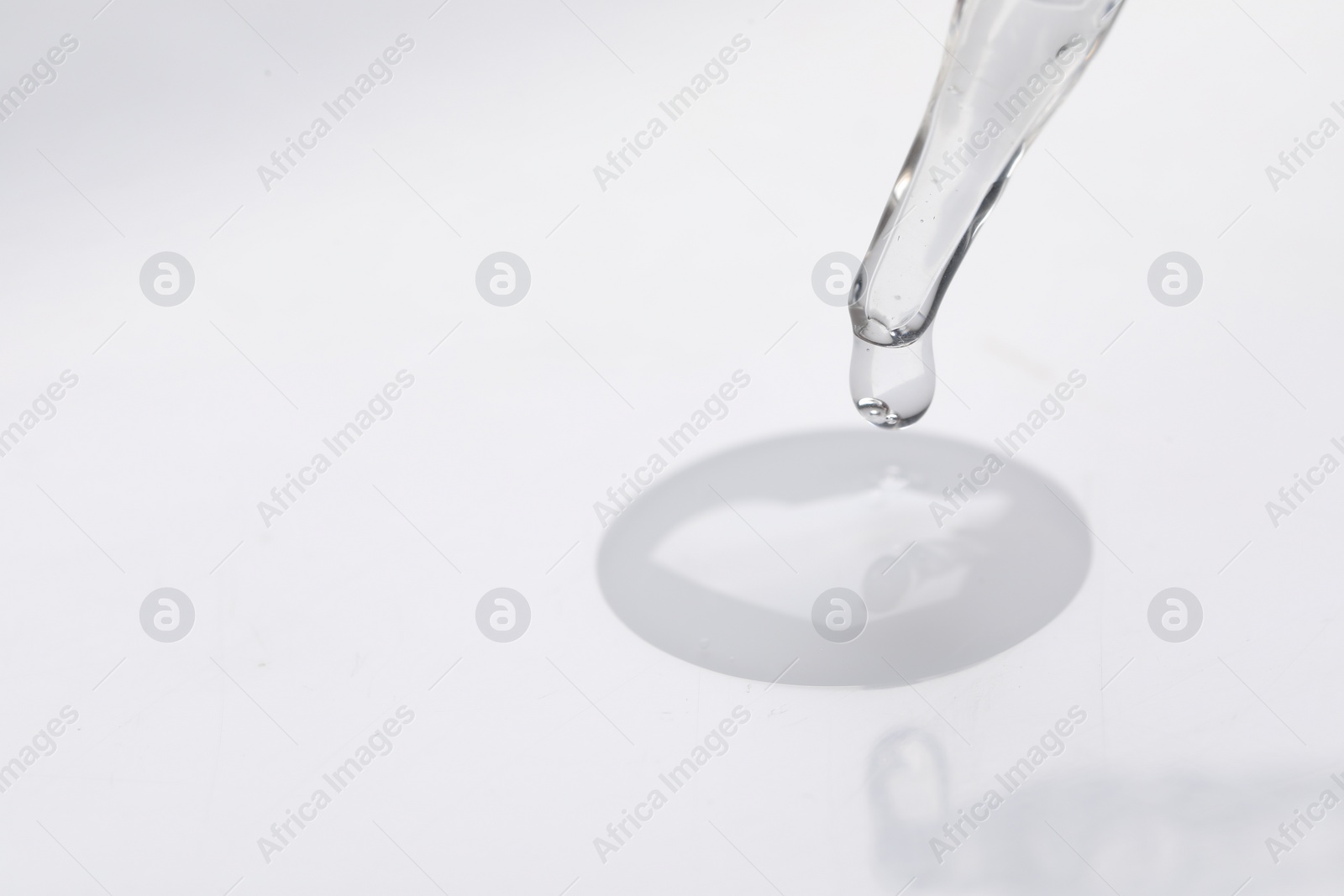 Photo of Glass pipette and transparent liquid on white background, closeup. Space for text