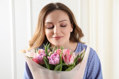 Photo of Young woman with bouquet of beautiful tulips indoors