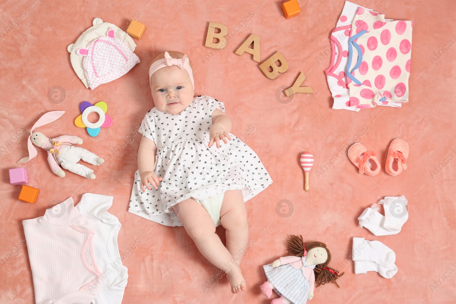 Photo of Cute little baby with clothing and accessories on color blanket, top view