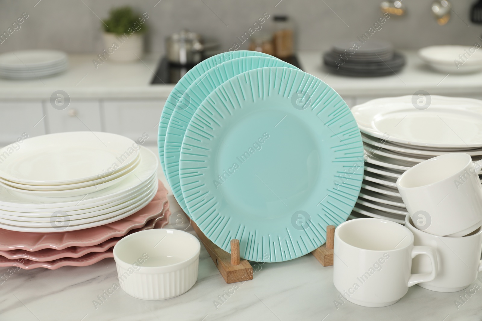 Photo of Clean plates, cups and bowl on white marble table in kitchen