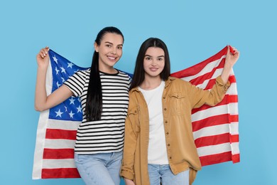4th of July - Independence Day of USA. Happy woman and her daughter with American flag on light blue background