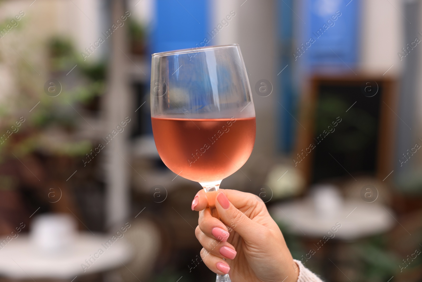 Photo of Woman holding glass of rose wine outdoors, closeup