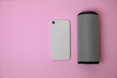 Portable bluetooth speaker and smartphone on pink background, flat lay with space for text. Audio equipment