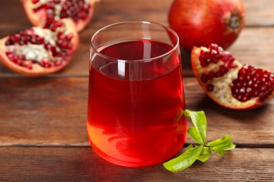 Photo of Tasty pomegranate juice in glass and fresh fruits on wooden table, closeup