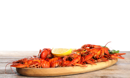 Photo of Delicious boiled crayfishes on wooden table against white background