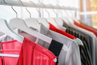 Photo of Stylish clothes hanging on wardrobe rack indoors, closeup