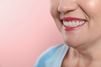 Photo of Smiling woman with perfect teeth on color background, closeup. Space for text