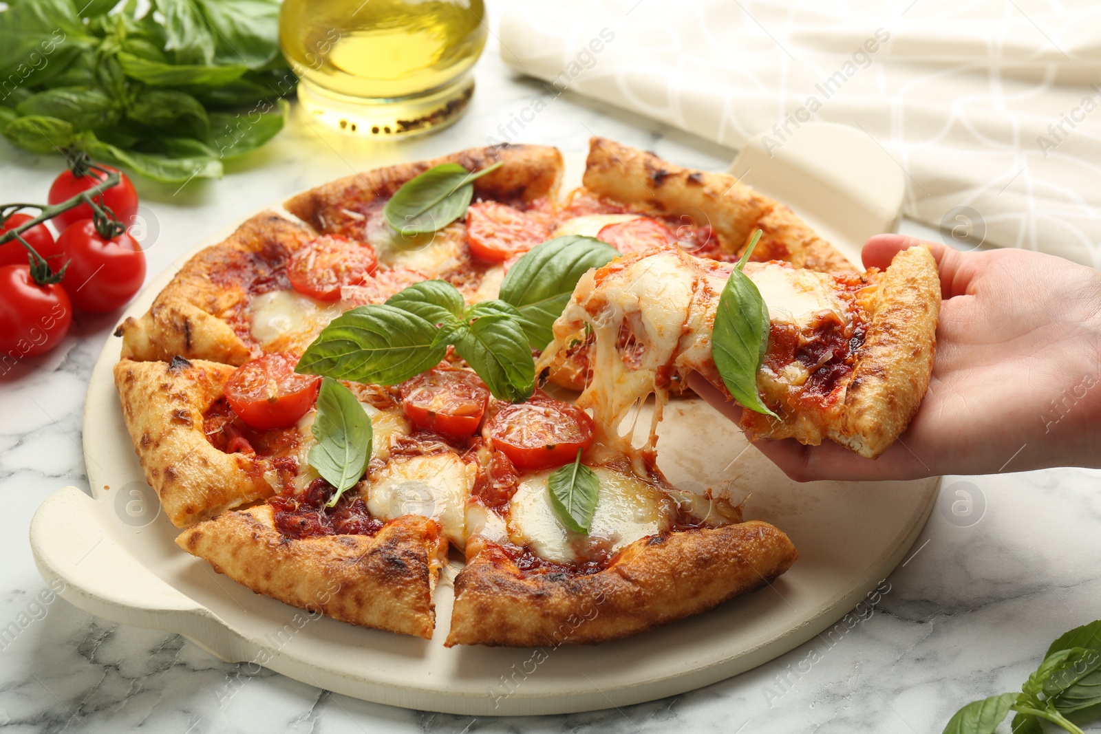 Photo of Woman taking piece of delicious Margherita pizza at white marble table, closeup