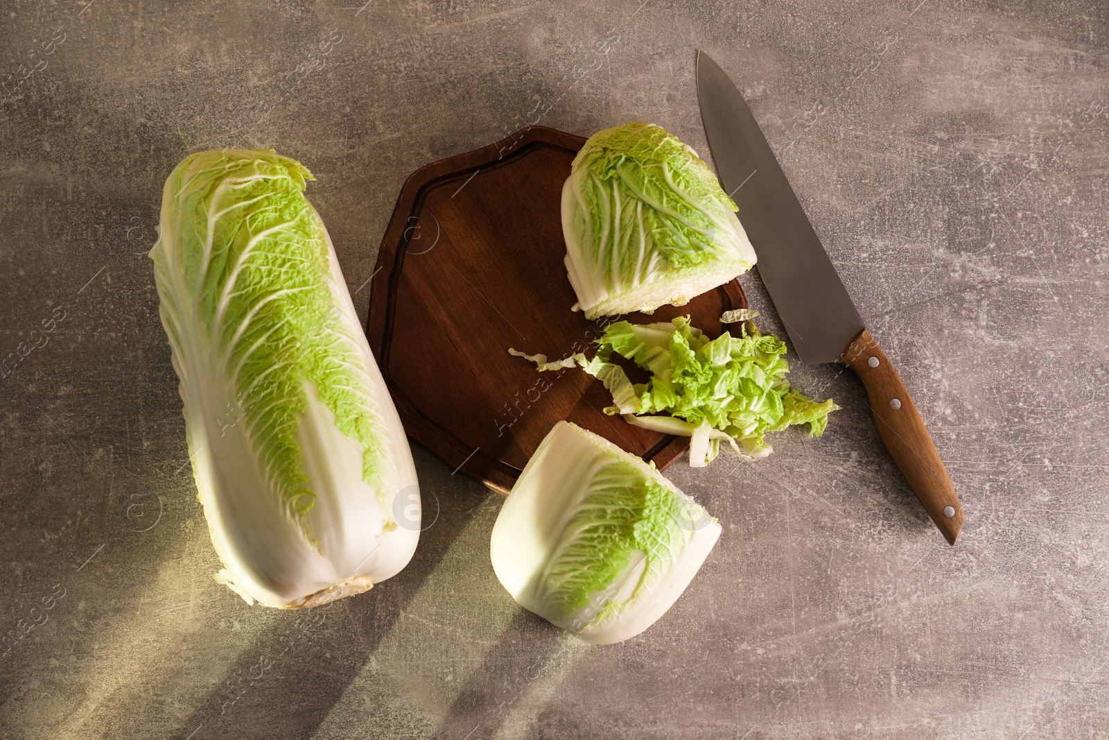 Photo of Whole and cut fresh Chinese cabbages on light grey table, flat lay