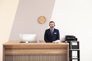 Portrait of receptionist working at desk in modern hotel