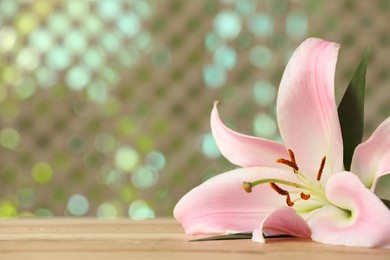 Photo of Beautiful pink lily flower on wooden table, space for text