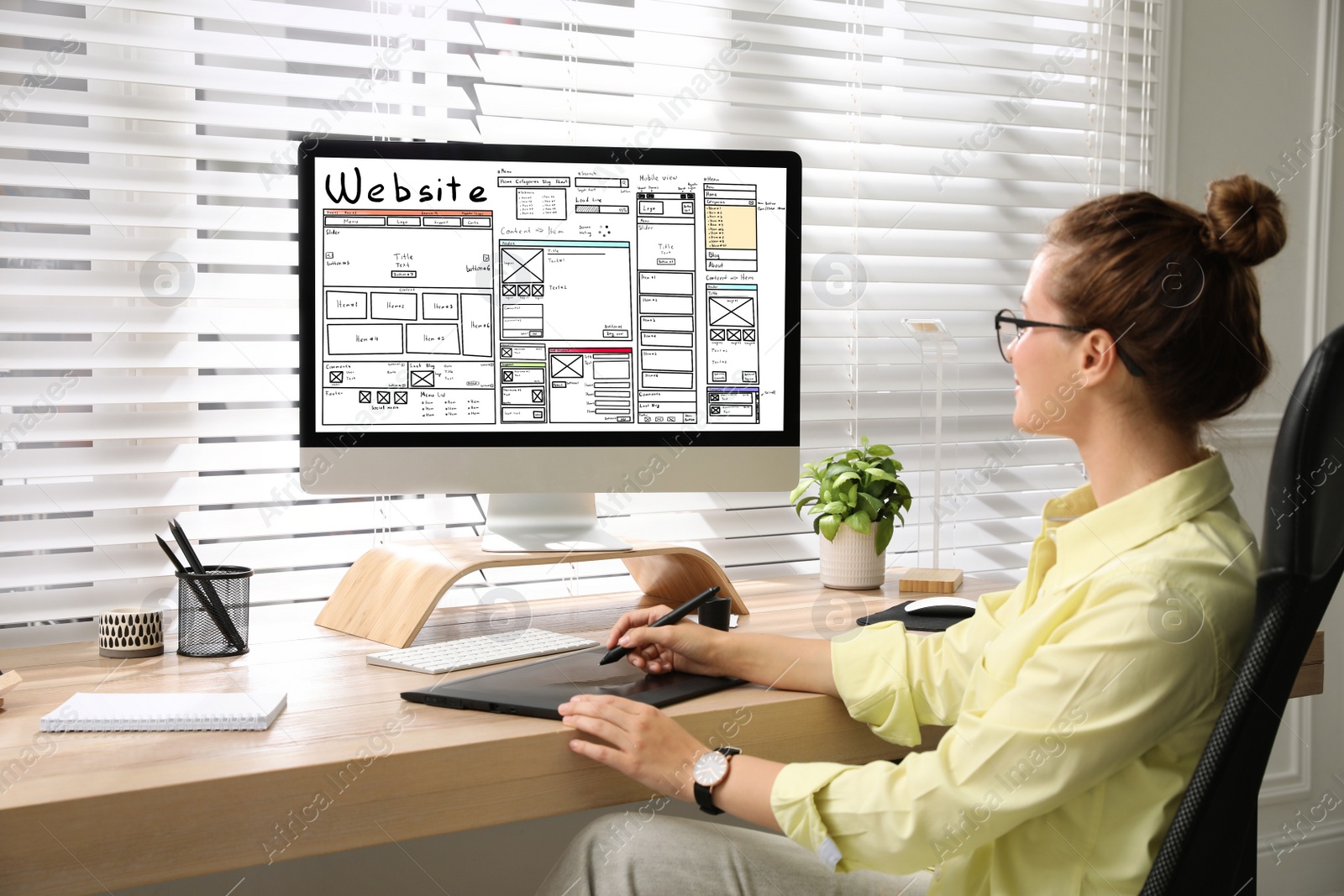 Image of Designer creating website on computer at wooden table