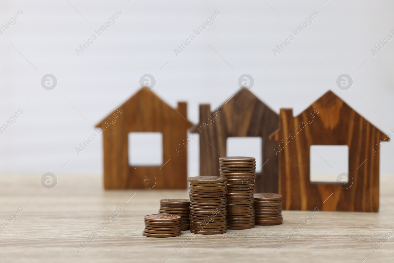 Photo of House models and stacked coins on wooden table