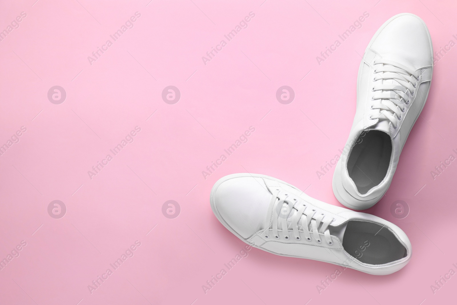 Photo of Pair of stylish white sneakers on pink background, top view. Space for text