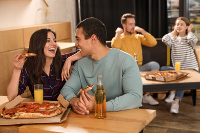 Young couple eating delicious pizza in cafe