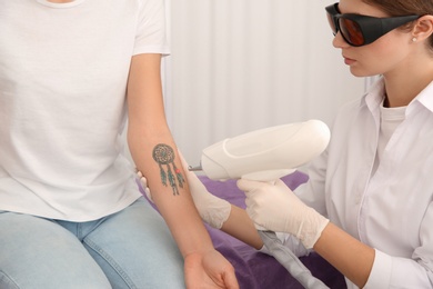 Photo of Young woman undergoing laser tattoo removal procedure in salon