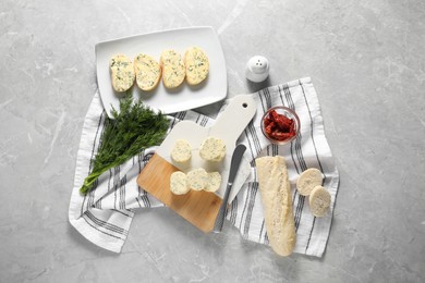 Photo of Tasty butter with dill, chili peppers, bread and knife on grey marble table, top view