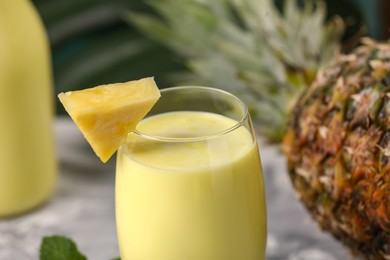 Photo of Tasty pineapple smoothie in glass and fruit on table, closeup