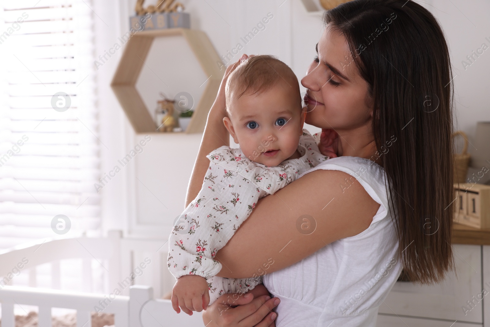 Photo of Happy young mother with her baby daughter in nursery