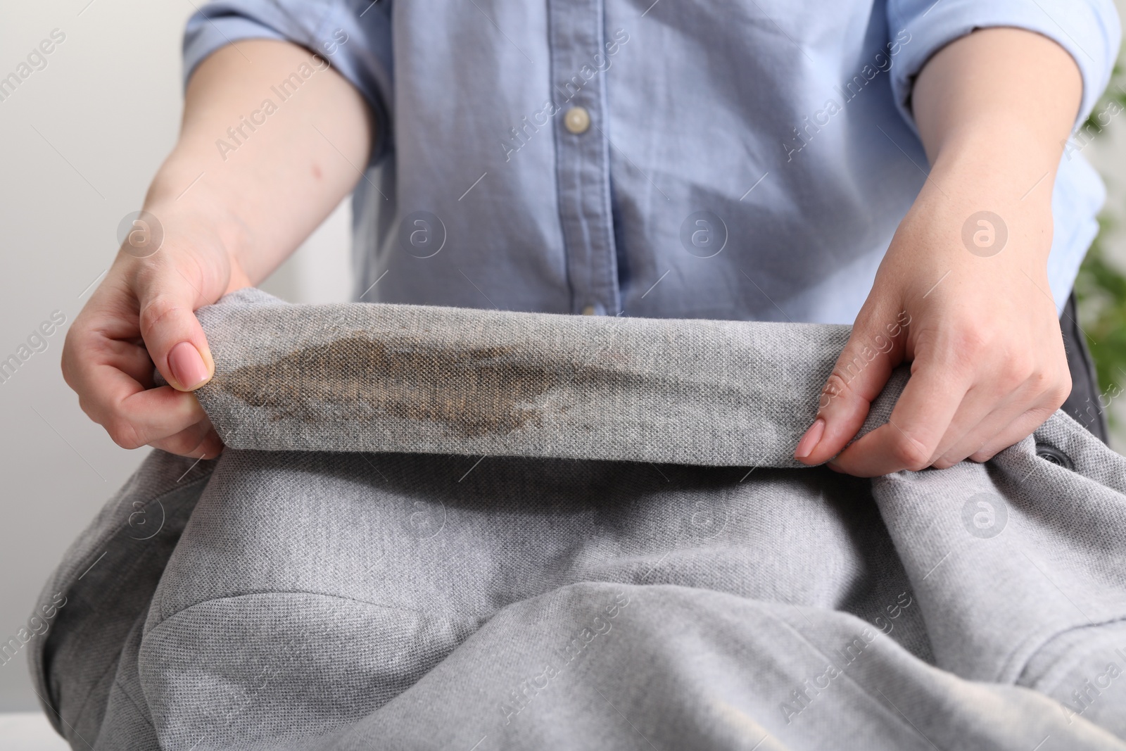 Photo of Woman showing stain from coffee on jacket against blurred background, closeup