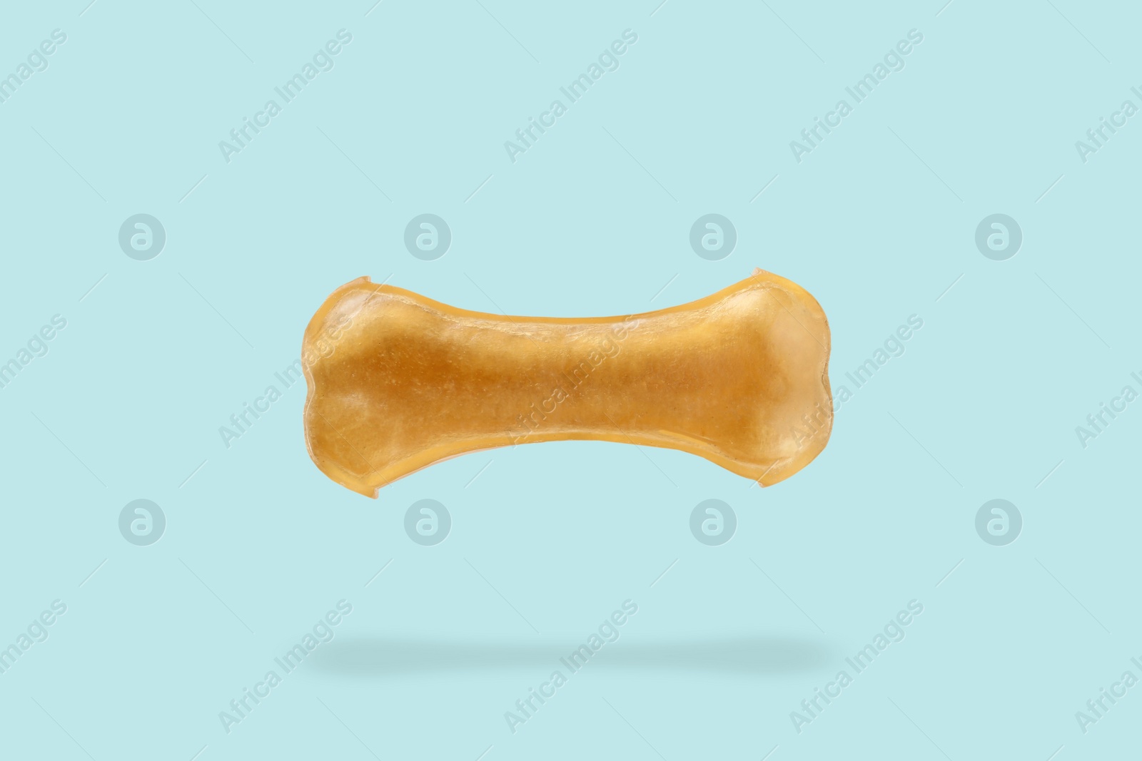 Image of Bone dog treat in air on light blue background