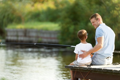 Dad and son fishing together on sunny day. Space for text