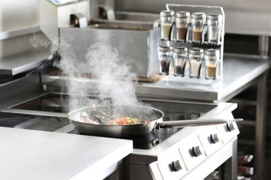 Photo of Cooking tasty food on stove in restaurant kitchen