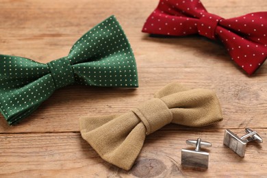Photo of Stylish color bow ties and cufflinks on wooden background